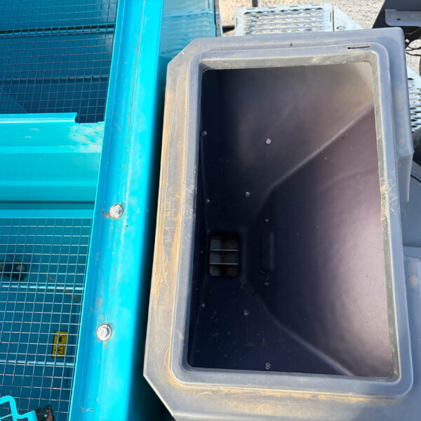 Close-up of blue metal frame and a black plastic container among industrial equipment pieces.