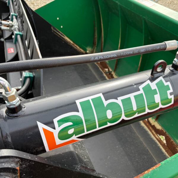 Hose labeled ALFAGOMMA attached to hydraulic fittings on green construction equipment.