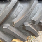 Stacked large, heavy-duty tire treads leaning on a wooden pallet outdoors.