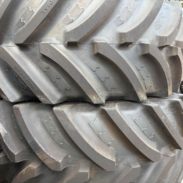 Close-up of stacked heavy-duty tractor tires with deep zigzag treads outside.