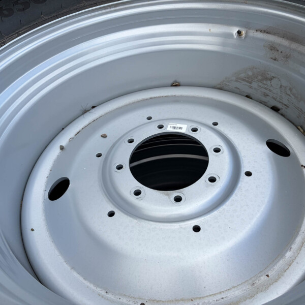 Close-up of a silver steel car wheel rim with multiple lug holes and some dirt along the edge.