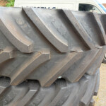 Stack of large black rubber tracks stacked outdoors, with a white van visible in the background.