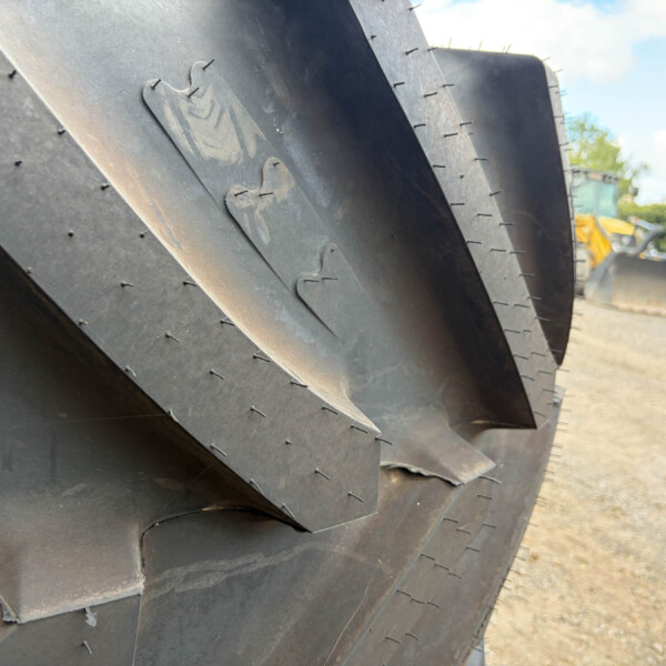 Close-up of stacked black steel plates with rivets, showing curved edges and worn metal texture in an outdoor yard.