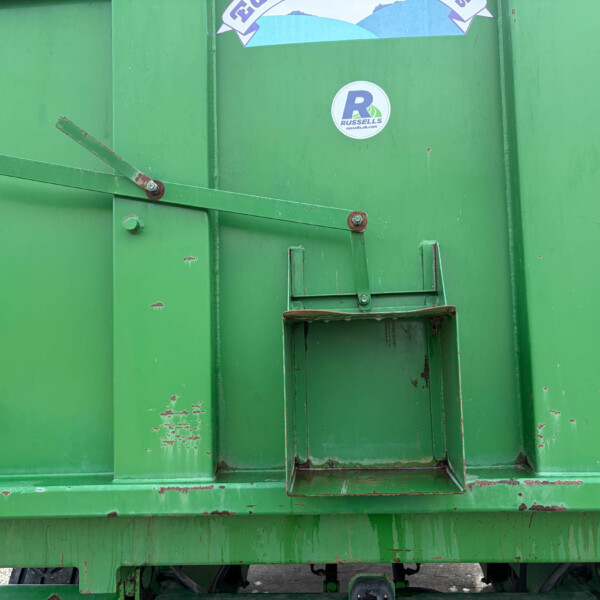 Close-up of a green industrial container door with a rusted support arm and a circular Russell's sticker nearby.