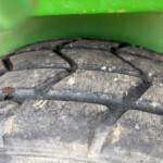 Close-up of a worn, dusty tire tread with a green metal frame in the background.