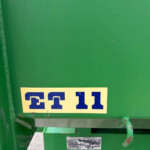 Close-up of a green industrial surface with a yellow label bearing blue letters and a rope looping along the left edge.