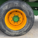 Close-up of a large tractor tire with a yellow rim mounted on green agricultural equipment