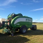 Green McHale Fusion vari bale harvester on a grassy field under a blue sky; large agricultural equipment with white logo panel visible.