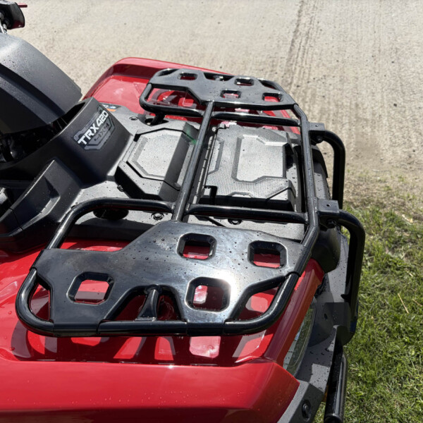 Red ATV from above with black front cargo rack and wet surface droplets on red body.