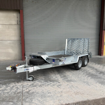 Industrial trailer with a metal ramp and spare tire parked in front of a large corrugated metal shutter doors.