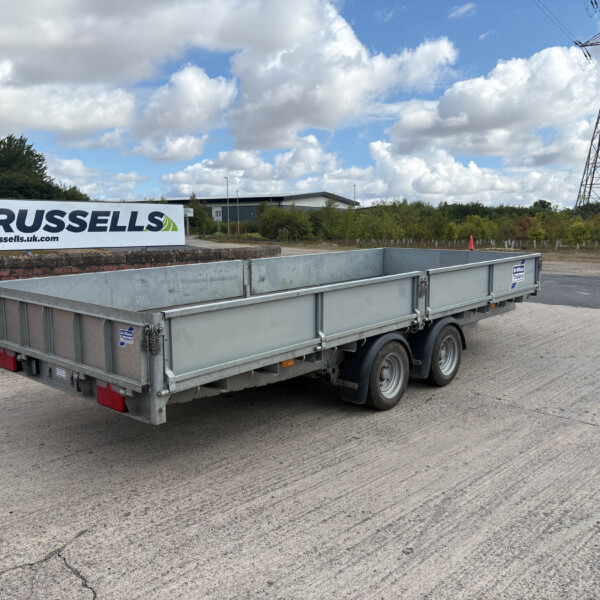 A large metal trailer parked on a paved lot beside a Russell's sign reading russells.uk.com in the foreground.