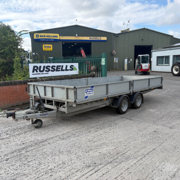 Industrial yard with a large trailer in the foreground and a grey warehouse in the background, Russell's branding on the building signage, green fencing nearby.