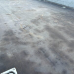 Close-up of a dark gray metal floor with a diamond plate texture and scattered dirt and small fasteners.
