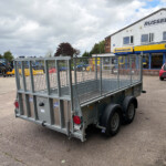 Metal trailer in foreground outside a farm equipment shop, with Russell's signage and a blue-and-yellow New Holland Agriculture store facade in the background