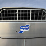 Front view of a gray trailer with a large curved metal grid grille and the Ifor Williams Trailers logo visible on the side panel.