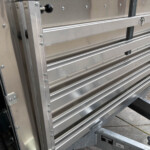 Side view of a ribbed aluminum trailer wall with bolts and vertical supports