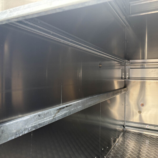 Interior of a stainless steel industrial cabinet with rails and panels