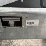 Close-up of a galvanized trailer frame with the Ifor Williams Trailers plate, showing model numbers, serial/barcode, and weight rating