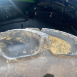 Close-up of a muddy, black tire and wheel well, showing dirt splatters and metal bolts above the tread.