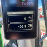 Close-up of a tractor dashboard showing 'Run Pages' and an hour meter reading (hours) with an outdoor background.