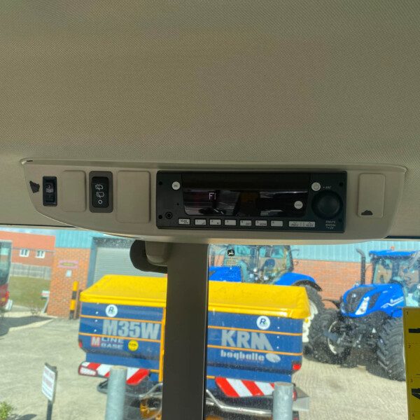 Inside a vehicle cabin with overhead controls and radio, view through windshield of a construction site outside.