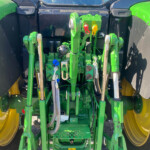 Rear tractor three-point hitch and hydraulic control levers in a green frame with yellow wheels; close-up of service connections and linkages.
