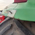 Close-up of a worn green metal panel with a small lever and a metal plate, dirt and chipped paint visible.