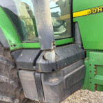 Close-up of a green John Deere tractor showing a mud-covered steps and wheel near the cab door and window