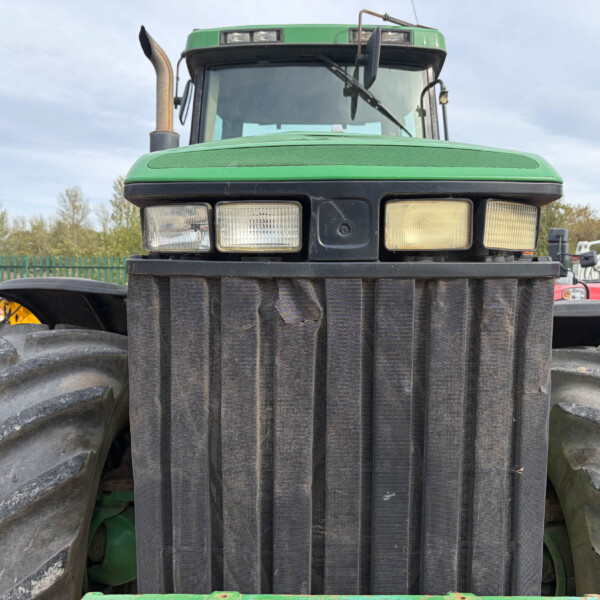 Close-up of a green tractor's front, showing large black grille, dual headlights, and oversized tires on either side.