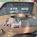 Close-up of a dusty tractor cab dashboard with dials, switches, and gear levers