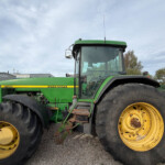 Green John Deere tractor with oversized yellow wheels parked in an outdoor lot.