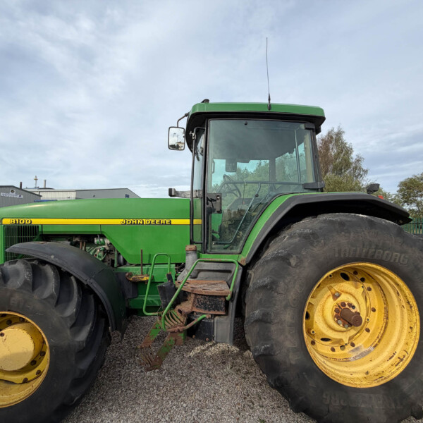 Green John Deere tractor with oversized yellow wheels parked in an outdoor lot.