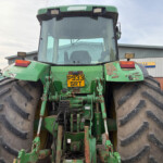 Rear view of a large green tractor with oversized tires, license plate P933 SRT, parked in an industrial yard.