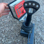 Close-up of a red KUHN control box mounted on a piece of agricultural equipment with knobs and a red joystick panel.