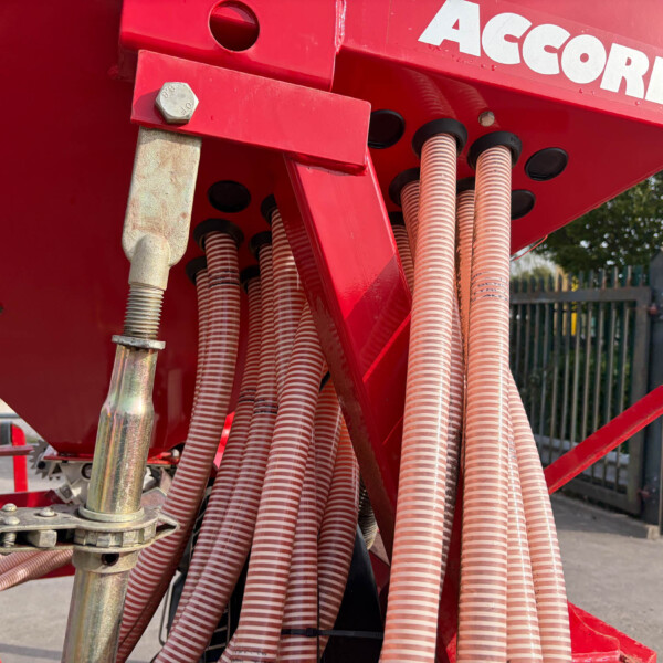 Close-up of red hydraulic machinery with multiple corrugated pink hoses and metal fittings outdoors.