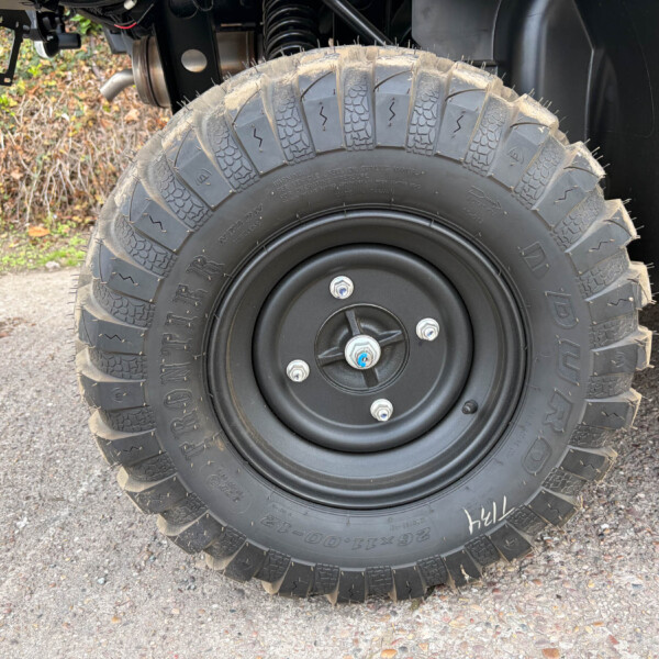 Close-up of a large off-road tire with aggressive tread mounted on a black wheel on a vehicle