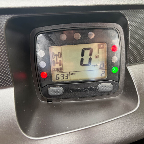 Kawasaki digital instrument cluster showing speed 0 mph, gear N, 2WD, time 6:33, with red warning lights nearby