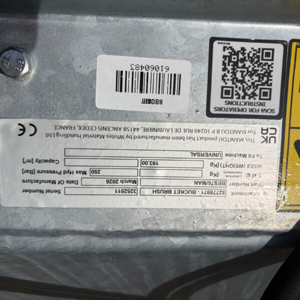 Close-up of a metal surface with a white barcode label and a QR code, beside a yellow safety warning label and a bolt head nearby.