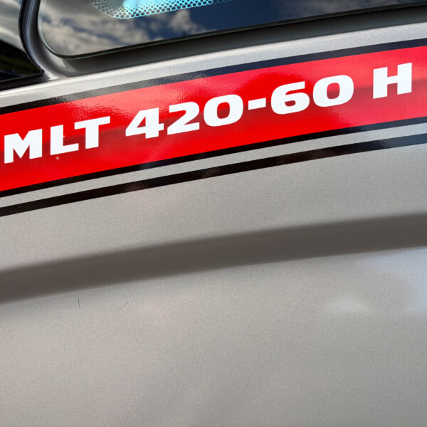 Close-up of a car body with a bold red stripe decal reading 'MLT 420-60 H' beside a window and dotted pattern.
