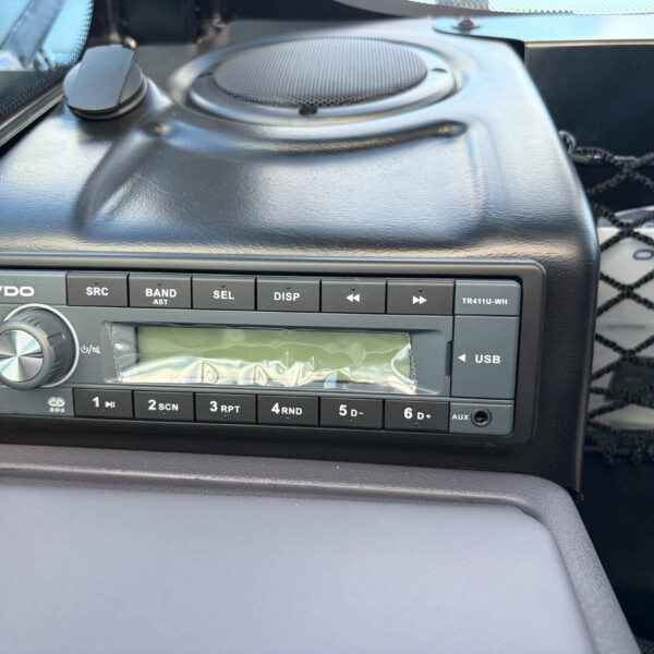 Close-up of a car stereo head unit in a black dashboard, showing the VDO unit with a circular volume knob and labeled buttons (SRC, BAND, SEL, DISP) and a USB port.