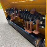 Close-up of rusted metal blades with bolts inside a yellow industrial machine enclosure