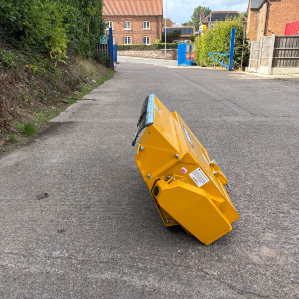 Yellow construction barrier on a road with blue gates and brick houses in the background.