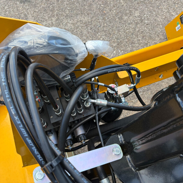 Close-up of hydraulic hoses and fittings inside a yellow industrial machine frame.