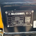 Close-up of a black identification plate on a yellow machine, showing the brand 'McCONNEL' and model/serial information with a QR code nearby