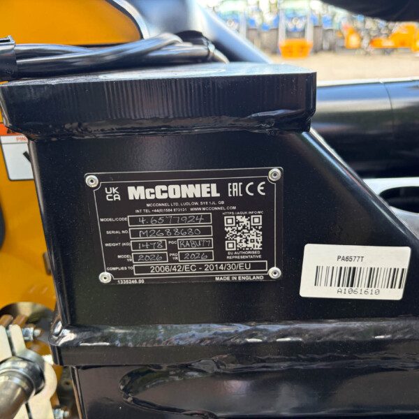 Close-up of a black metal control housing with a McCONNEL identification plate, barcode and QR area, mounted on yellow machinery.