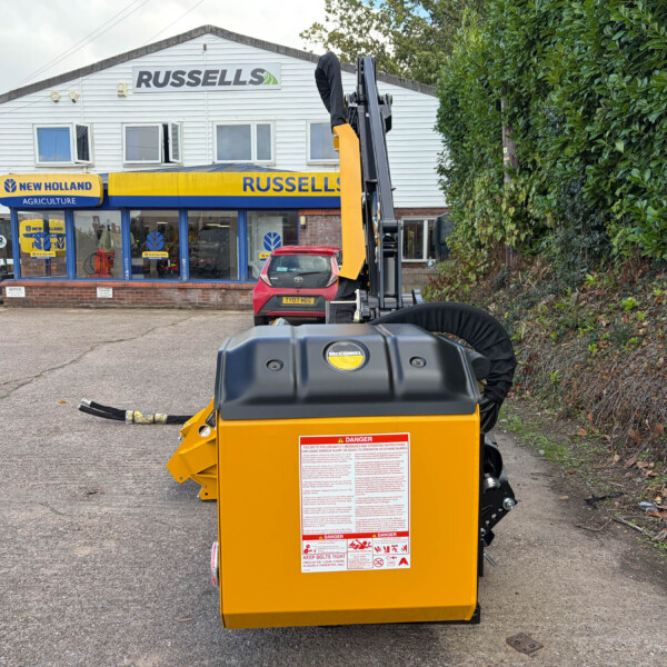 Yellow industrial machine in the foreground outside Russell's store, with a New Holland Agriculture sign on the blue storefront behind it.