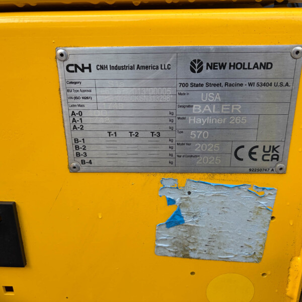 Metal identification plate on a yellow machine showing CNH Industrial America LLC and New Holland branding with model/spec details nearby on the plate.