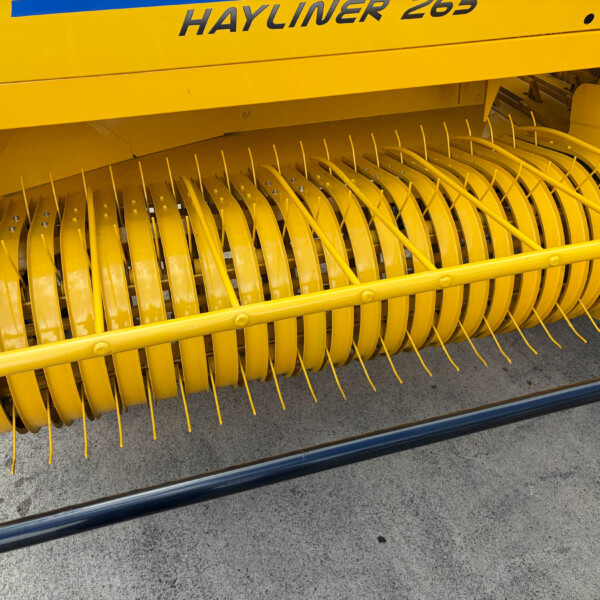 Close-up of a yellow combine harvester header reel with curved tines for gathering crops.