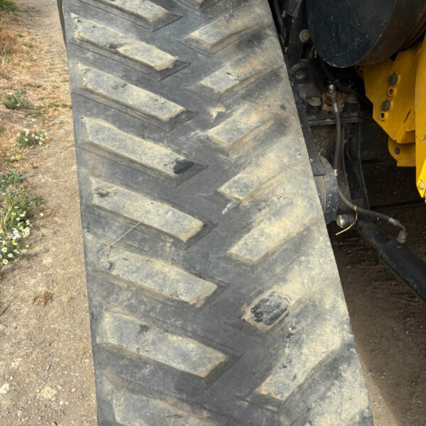 Close-up of a dusty tractor tire with deep tread pattern on a dirt path