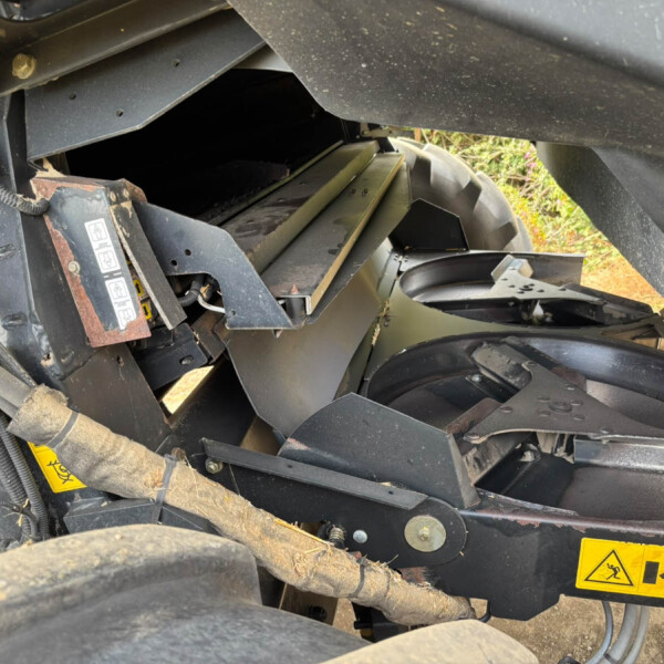 Close-up of heavy machinery interior with metal framing, cables, and yellow warning labels.